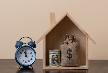 A symbolic wooden house, a stack of US$1 bills and a money bag with a dollar symbol