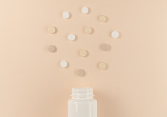 Pills and bottle on beige background. Flat lay, top view.