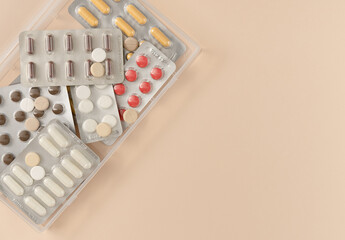 Many blisters with different pills on beige background. Flat lay, top view. Copy space