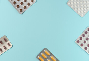 Frame of many blisters with different pills on blue background. Flat lay, top view. Copy space