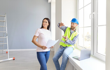 Woman client and architect discuss the home renovation, reviewing a blueprint together. They...