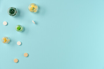 Tablets in glass jars on blue background. Flat lay, top view. Copy space
