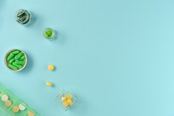 Tablets in jars and pillbox on blue background. Flat lay, top view. Copy space