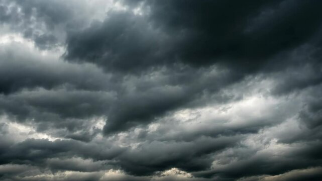 Dark storm clouds gather over a landscape, signaling upcoming rain and thunderstorms during late afternoon
