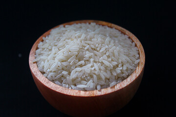 Zakat fitrah concept: Wooden bowl filled with rice on a black background.
