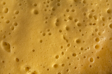 Surface Of Fried Pancake Dough With Tiny Holes. Yellow Background Of Baked Omelette Dough. Fresh Pancake Batter.