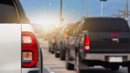 Rear side of white pickup car with turn on brake light. Many pickup trucks are parked in queues on the road during business hours.