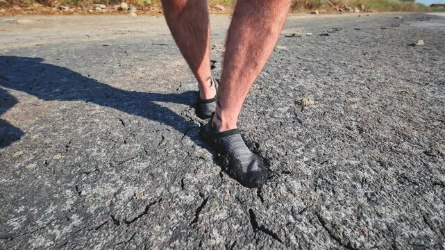 A man walks through mud and swampy cracked earth.