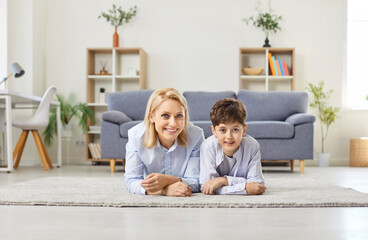 Loving mother, caring woman with little son lying on new warm clean carpet floor enjoy time...
