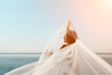 A woman stands on a beach with a white veil over her head. The scene is serene and peaceful, with...