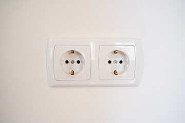 A white double electrical wall outlet. European type power socket on a white wall close-up....