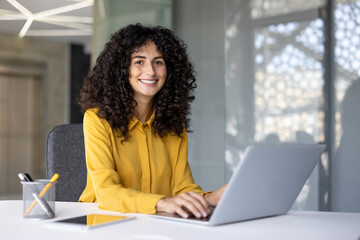 Portrait of a happy successful businesswoman at her workplace inside the office. The woman is...