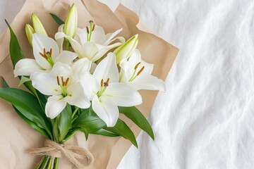 White lilies bouquet wrapped in paper on soft fabric background   © bashkirovaphoto