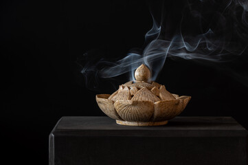 Ceramic carved incense burner on a black background.