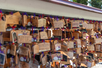 Blurred wooden ema plaques with wishes hang in a Buddhist temple in Japan creating a bokeh effect and an atmosphere of spiritual traditions