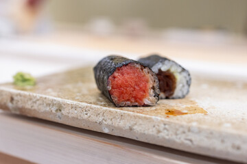 Two hosomaki sushi rolls with finely chopped tuna and dried calabash filling wrapped in nori placed...