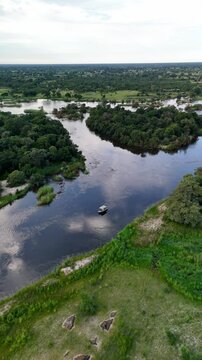 Vertical aerial drone view of the Okavango River at sunrise on the Namibia-Angola border, Africa. The river features a shore and green vegetation.