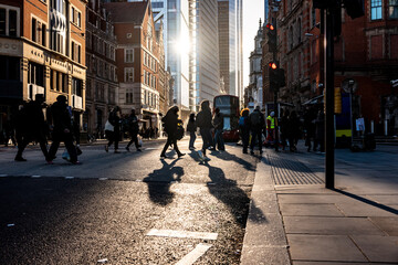 People crossing the street in London at sunset with long shadows