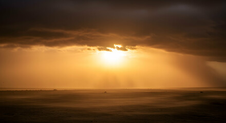 Fototapeta premium Golden Sunlight Breaks Through Dark Clouds Over a Misty Landscape