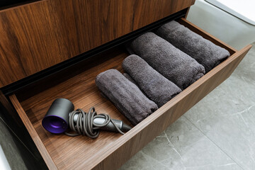 A meticulously organized bathroom cabinet features a drawer that is filled with neatly arranged...