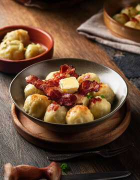 A bowl of traditional Norwegian raspeballer dumplings served with crispy bacon and melted butter on a rustic plate