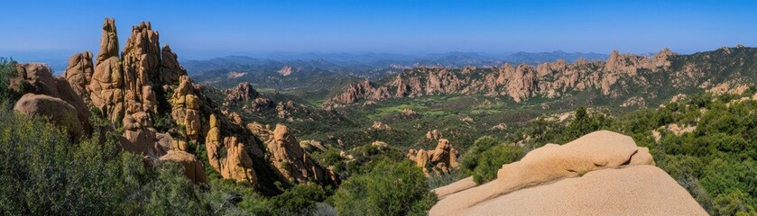 Naklejka premium A wide panoramic view of mountainous terrain under blue skies