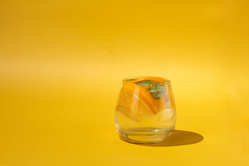 glass with orange cocktail on yellow background