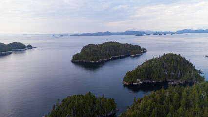 Obraz premium Aerial landscape of the coast of British Columbia. Taken near Calvert Island BC, small forested islands dot the calm ocean with mountains in the distance