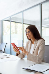 Middle eastern or hispanic business woman working on smartphone mobile phone at office. Young IT...