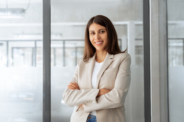 Confident leader smiling latin hispanic, middle eastern business woman standing arms crossed in...