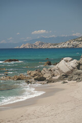 A stunning view of the Sardinia coast featuring turquoise water, rocks, and a sandy beach.