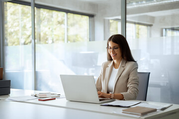 Young professional it specialist latin hispanic business lady working on laptop pc sitting at desk...