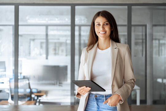 Portrait at camera of CEO businesswoman manager using pc tablet for sales management, financial operations, online banking. Latin or middle eastern elegant business woman working on computer at office