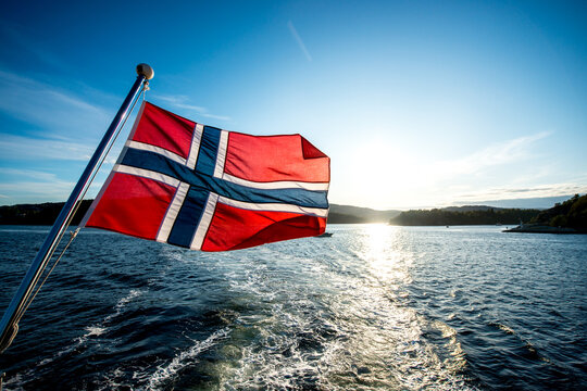 Norwegian flag on a ship or boat with the Oslo fjord in Norway in the background, sightseeing ferry