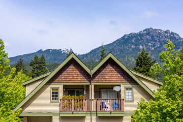 Naklejka premium Top of luxury house with shingle roof, red and yellow trees and nice windows in Summer in Vancouver, Canada, North America. Day time on June 2024.