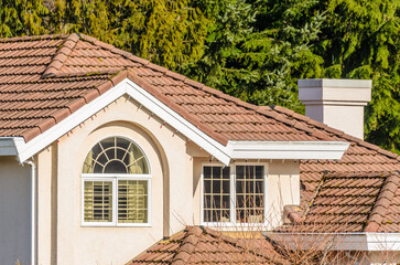 Top of luxury house with shingle roof, red and yellow trees and nice windows in Summer in...
