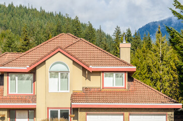 Top of luxury house with shingle roof, red and yellow trees and nice windows in Summer in Vancouver, Canada, North America. Day time on June 2024.