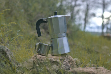 Aluminum coffee maker with aluminum cup in a forest, camping