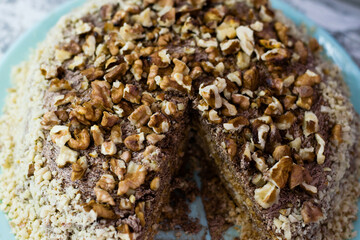 Delicious homemade cake with meringue, peanuts and walnuts on a light background. Sliced cake on a...
