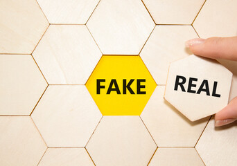 Real or Fake symbol. Concept word Real or Fake on wooden blocks. Businessman hand. Beautiful yellow...