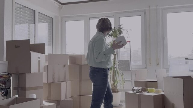 An elderly woman of 65 years old is happy to move. She dances among the moving boxes.
