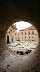 Terracotta roofs and outdoor cafes framed in a stone archway