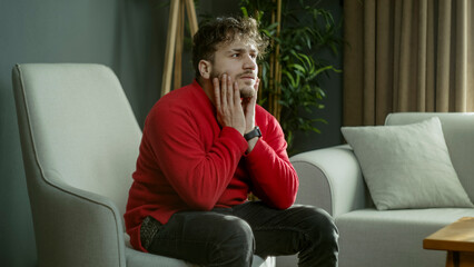 Young Man Sitting Thoughtfully in a Cozy Living Room, Lost in Deep Thoughts