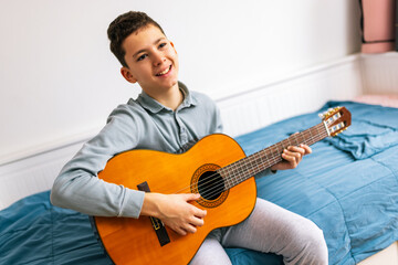Little boy plays classical guitar at home.
