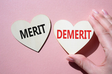 Merit or Demerit symbol. Concept word Merit or Demerit on wooden hearts. Businessman hand....