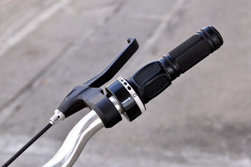 close up bicycle grip handlebar with manual gear and brake lever, black rubber grip and silver...