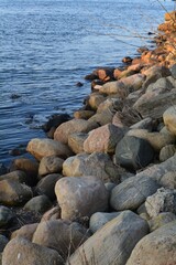 Nordic shoreline, where large, rounded rocks meet the gentle waves of a deep blue sea