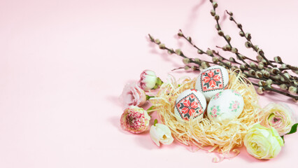 Painted Easter eggs and willow branches are decorated with natural fresh flower heads