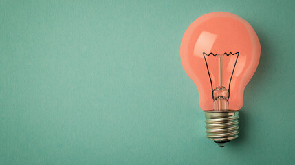 A pink lightbulb against a teal background, symbolizing creativity and innovation in a minimalist design.