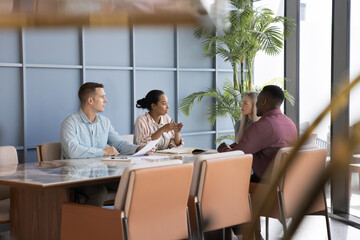 Professional team leading formal discussion seated at conference desk in modern office, engaged in project updates sharing, strategy planning, or brainstorming ideas. Seminar, briefing event, teamwork